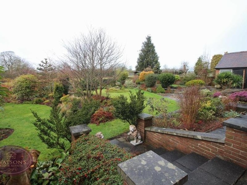 Steps lead down to the back garden, which also includes a paved patio, a brick-built outhouse with power and storage space, and a timber-built summer house.