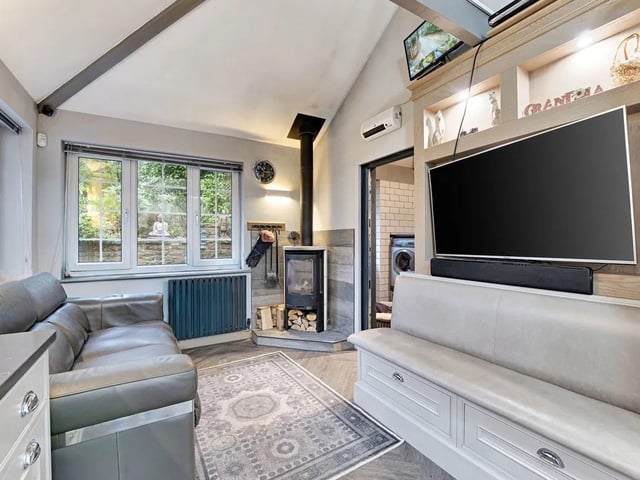 The kitchen flows naturally into a cosy family snug area, where a contemporary log-burning stove provides warmth and atmosphere.
