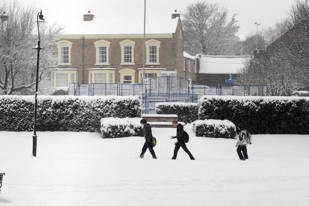 Three youngsters tredging through the snow.