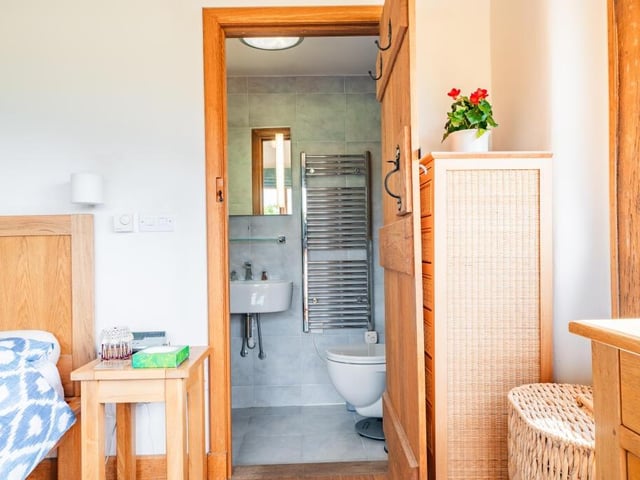 As you can see, the master bedroom has access to an en suite wet room with underfloor heating. It is finished with blue tiles, a round feature sink, built-in storage and a heated towel-rail.