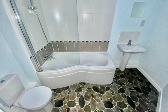 The smart bathroom comprises a three-piece white suite, with bath and shower over, wash hand basin and low-flush WC.
