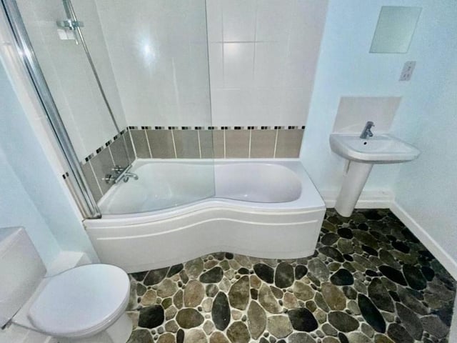 The smart bathroom comprises a three-piece white suite, with bath and shower over, wash hand basin and low-flush WC.