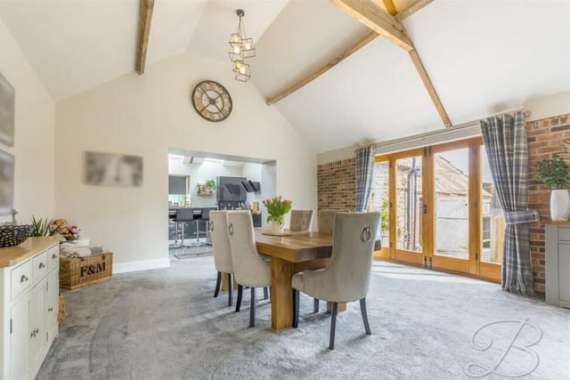 Flowing seamlessly from the living room is this dining area, with another high ceiling, more wooden beams and a set of wooden French doors leading out to the garden.