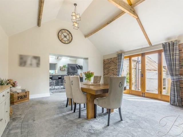 Flowing seamlessly from the living room is this dining area, with another high ceiling, more wooden beams and a set of wooden French doors leading out to the garden.