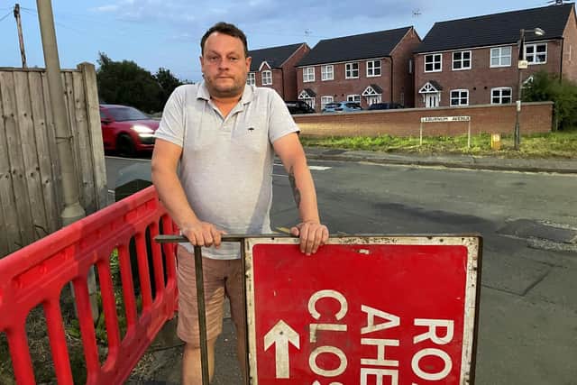 Coun Jason Zadrozny with the road closure signs at Laburnum Avenue, Kirkby.