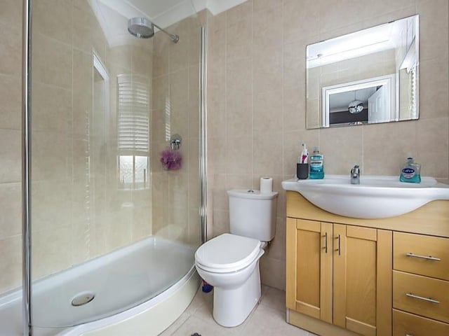 Here is the striking en suite bathroom to the master bedroom. It comprises a large shower cubicle, low-flush WC and wash hand basin with storage underneath.