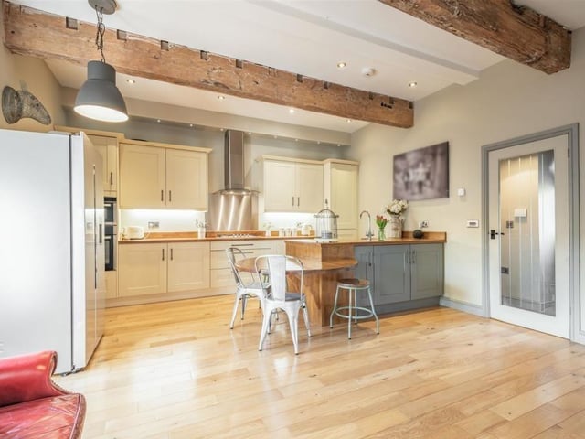This shot shows the large island in the kitchen/diner. Integrated stainless steel appliances include an oven, separate microwave, grill, and five-ring gas hob with extractor hood above.