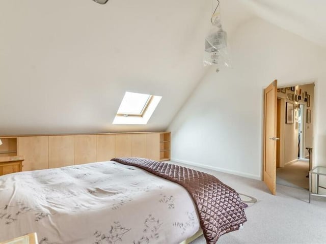 The first of the two bedrooms on the first floor is the largest, with vaulted high ceilings. There are custom-fitted maple/oak units on each side if the room, as well as open-glazed units for ornaments and an under-window seat with spotlights above. The main window faces the front of the property, but there is also a Velux window.