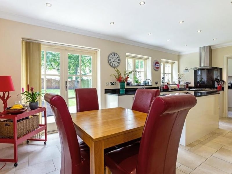 Let's start our tour of the Crow Hill Rise house in this contemporary dining kitchen, which has French doors that lead out to the garden. It incorporates high-gloss cream base units, a bank of tall units, a central chef's island and granite work surfaces.