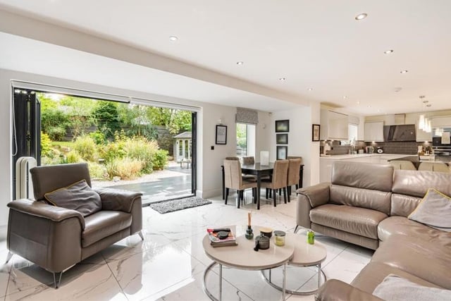 The dominant room on the ground floor is this open-plan living room and dining kitchen. It is superbly appointed, with bi-fold doors in the living area leading out to the back garden, and there is ample space for a dining table.