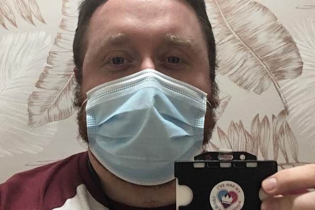 Staff member Danny Hendrie proudly shows off his vaccination sticker