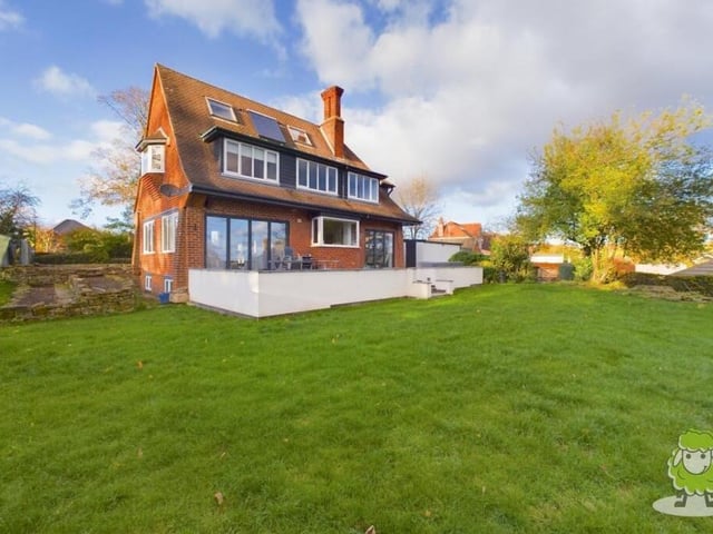 Stepping outside now, and here is a view from the rear of the imposing property. A garden terrace looks out over a well maintained lawn.