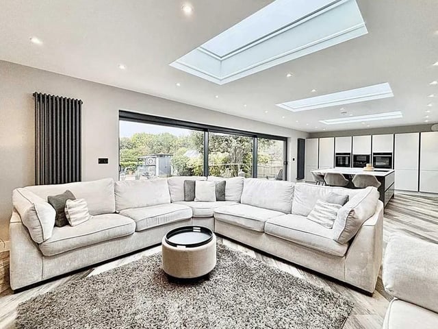 At the heart of the property lies a magnificent open-plan lounge and kitchen area, flooded with natural light thanks to expansive sliding glass doors that seamlessly blend indoor elegance with the beauty of the garden.