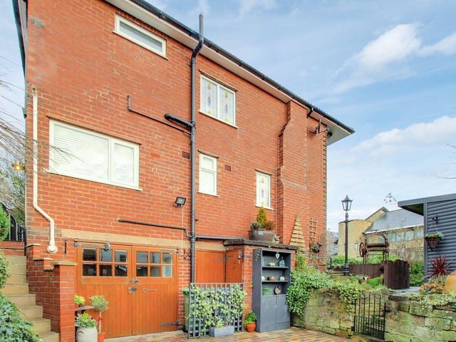 A side view of the property, which sits on a prominent and elevated corner plot, bordered on three sides by natural stone walls.
