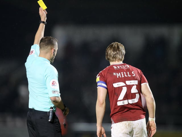 Joseph Mills of Northampton Town is shown a yellow card by referee Paul Howard.