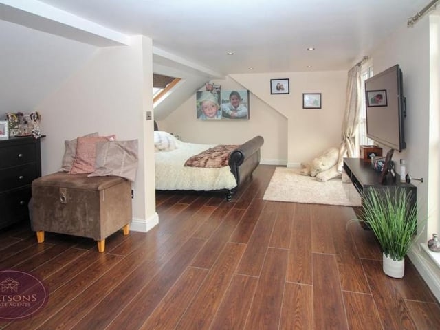 Up to the second floor now and let's marvel at the primary bedroom. It is a vast space with a Velux window above the bed, two more windows overlooking the back of the house, ceiling spotlights and eaves storage. Its open layout leads to an en suite bathroom.