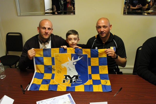 Lucky fan Charlie Ray has his flag signed by Adam Murray and Richard Cooper.