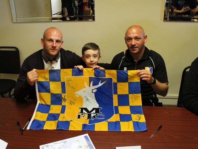 Lucky fan Charlie Ray has his flag signed by Adam Murray and Richard Cooper.