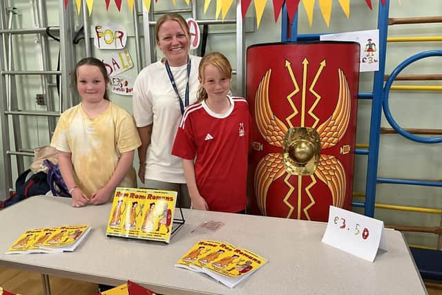 Abbey Hill's children and staff selling their published book 'Romans'