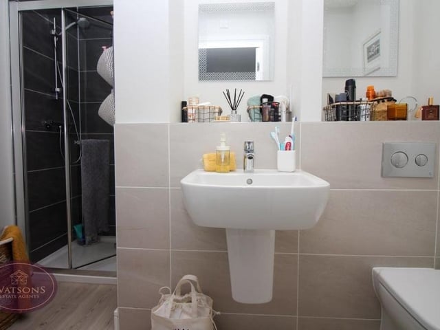 Here is the en suite bathroom to the main bedroom. A three-piece suite in white comprises a shower cubicle with mains-fed shower, a wall-mounted sink and a concealed-cistern WC. Not to mention a chrome, heated towel-rail and ceiling spotlights.