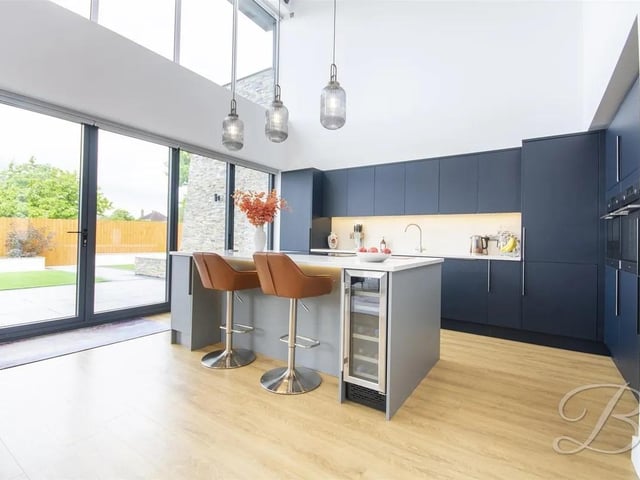The fully equipped kitchen features a range of integrated appliances, ample storage, and a striking central island providing additional preparation space and casual seating.