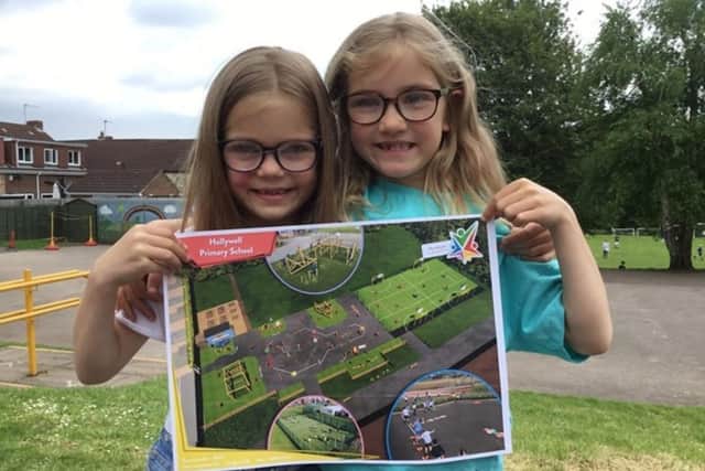 Sophie and Jessica holding up the design plans for their new school playground