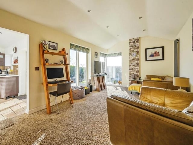 The rear extension has also helped to accommodate this spacious living room, which is beautifully finished, with spotlights and carpeted flooring. Large windows at the back and the side let in lots of natural light,.