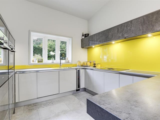 The kitchen features an integrated Bosch oven and microwave combi-oven, a warming drawer, an Elica downdraught induction hob, an integrated wine cooler, an integrated fridge/freezer, recessed spotlights and tiled flooring.