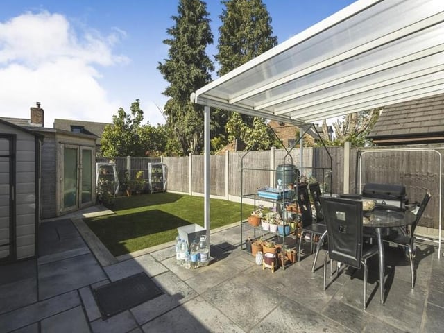 Our final photo shows the back garden from a different angle. In the foreground is a pleasant patio area with seating, while in the background is a summer house.