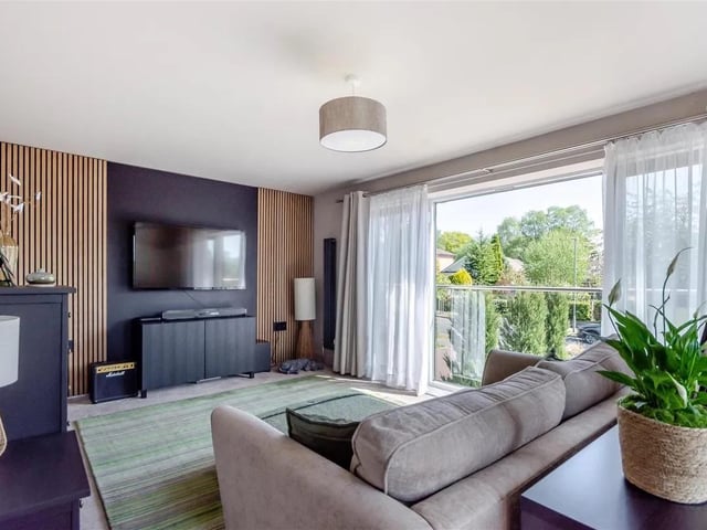 A large double bedroom currently utilised as a home cinema room with modern, vertical, floor-to-ceiling wood cladding features, two vertical radiators and three double glazed windowpanes and french doors/Juliet glass balcony to the front elevation.
