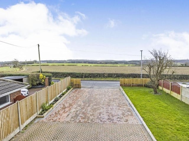 Stepping outside now, and here is the huge driveway that provides off-street parking space for more than ten vehicles and leads not only to the front of the house but also a secure garage. The image also shows the countryside views from the property.