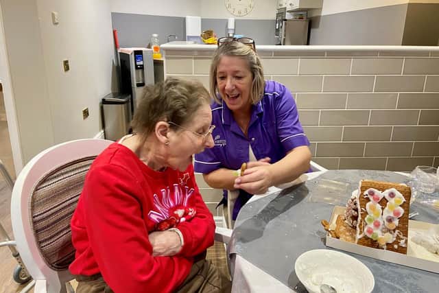 Resident Doreen try to eat the ginger bread man with staff member Julie