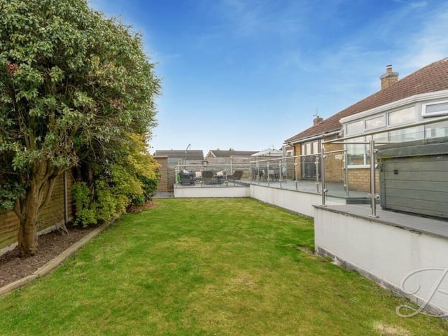 Running alongside the patio and hot tub area in the enclosed garden is this well-maintained lawn.