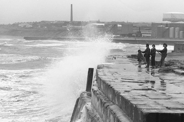 A group of sea anglers undeterred by heavy seas and flying spray in their bid to catch codling from the South Dock, Hendon in 1974.