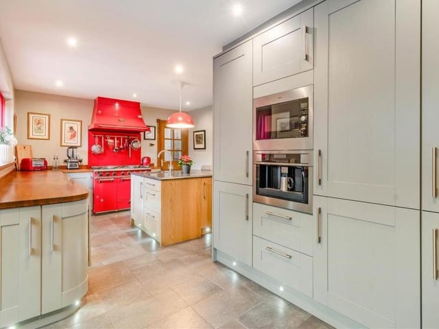 The kitchen and breakfast room is all about style. It includes an extensive range of contrasting shaker-style cabinets with brushed metal handles, comprising wall cupboards, base units and drawers, with wood surfaces above.