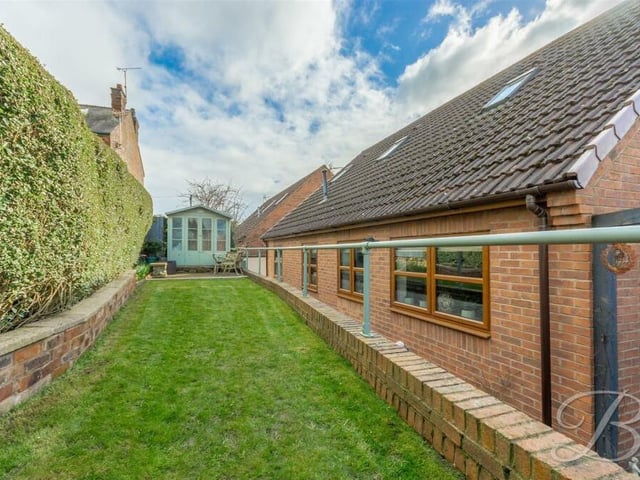 The rear garden features a lengthy, raised lawn that leads to a patio area.