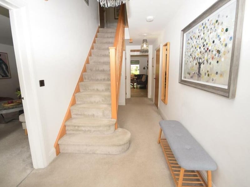 As we prepare to go upstairs, let's step into the inviting reception hall at the Rockcliffe Grange property. The stylish decor has warm, welcoming tones, and built into the staircase is a storage cupboard housing the CCTV system and underfloor heating system.