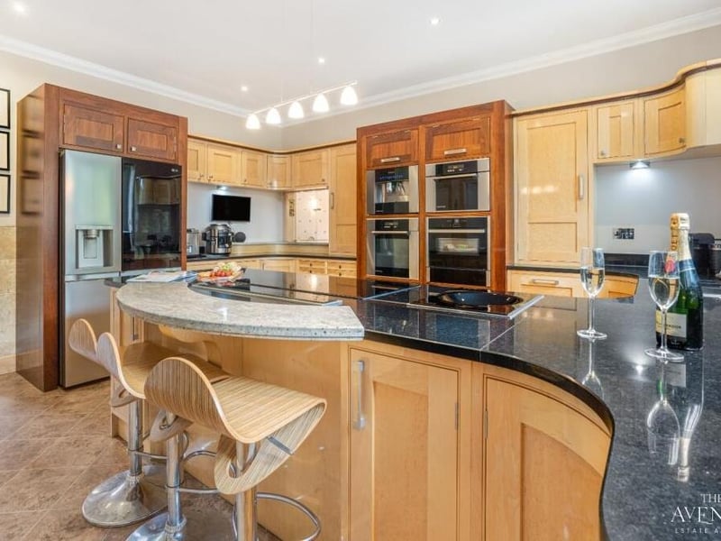 The kitchen includes a stunning island, perfect for food preparation, which doubles up as a breakfast bar. Other integrated appliances include a fridge/freezer, induction hob with extractor fan, and a coffee machine.