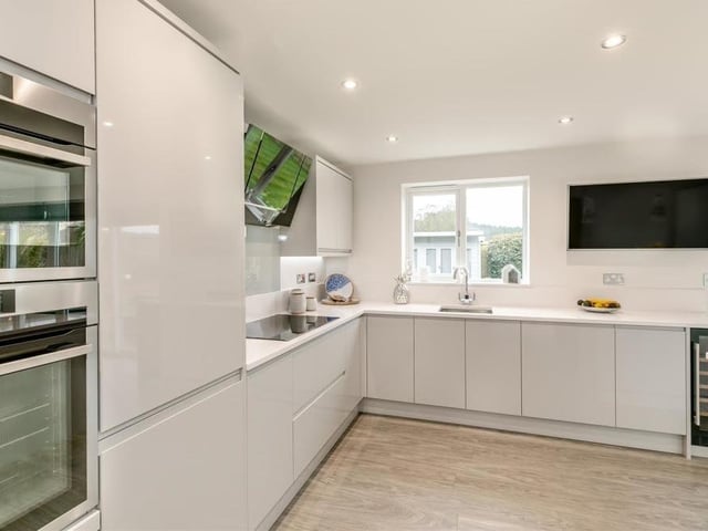 Integrated, stainless steel AEG cooking appliances in the sleek kitchen include a microwave combi oven and separate oven. Further appliances include a four-ring induction hob with AEG extractor hood above.