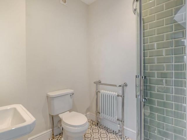 A tiled corner shower cubicle is the main feature of the second bedroom's en suite bathroom. There is also a pedestal wash hand basin, a low-flush WC, chrome towel-rail and ceiling spotlights.