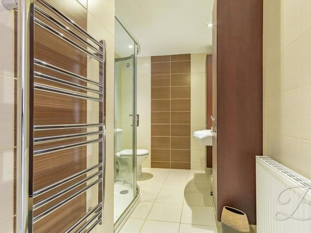Here is the modern en suite bathroom that is part of the master bedroom. The suite comprises an enclosed shower, low-flush WC, wash hand basin, vanity unit, downlights and a chrome, heated towel-rail.