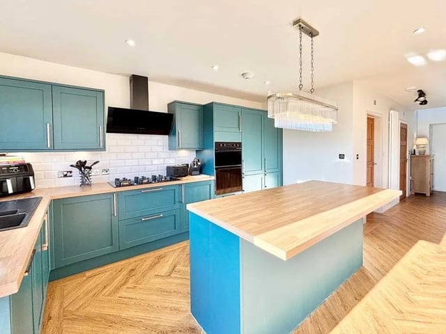 The stylish modern kitchen features an island, eye level double oven, six burner hob, extractor fan, dishwasher and wine cooler.