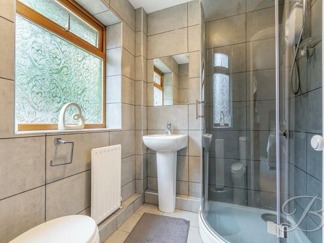 One of the bedrooms on the ground floor has access to this excellent en suite shower room. It has a curved walk-in shower cubicle, hand wash basin, low-flush WC and full-height tiling.