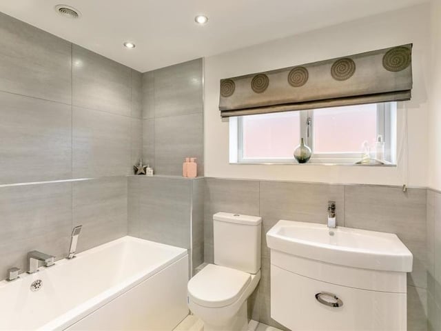 Our inspection of the first floor is completed in the family bathroom, which comprises a gorgeous three-piece white suite with chrome fittings. At the heart of it is a panelled bath with mixer tap, next to which are a vanity unit with wash hand basin and storage drawer, and a low-flush WC. There's also a heated towel-rail, attractive, modern tiling, and six ceiling spotlights.