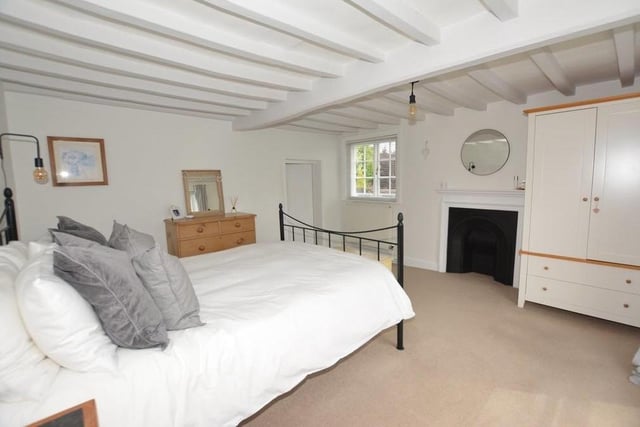Time to move up to the first floor, where three of the five bedrooms are situated, including this master. With its beamed ceiling and ornamental cast-iron fireplace, it has bags of character. Steps leads down to its en suite facilities.