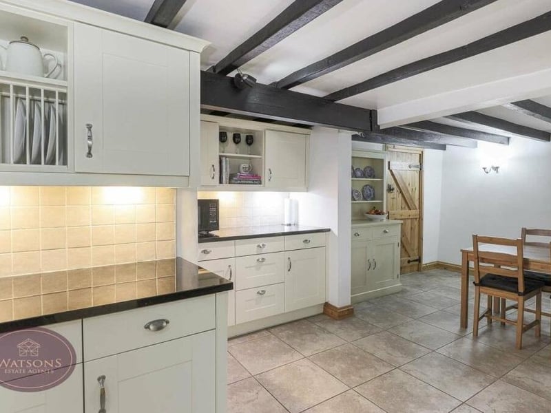 The dining kitchen is full of rustic charm, especially with its exposed ceiling beams. It is fitted with a range of matching shaker-style wall and base units.