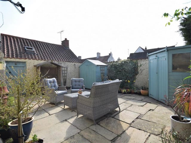 Imagine spending long, warm sunny days with friends in this enclosed courtyard garden. It's a pleasant seating area, surrounded by shrubs and plants.