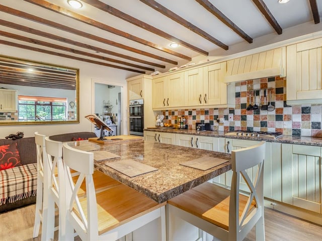 A host of integrated appliances within the kitchen include a double oven, a five-ring stainless steel gas hob and extractor hood above, dishwasher and fridge. A vinyl floor and ceiling spotlights are other features.