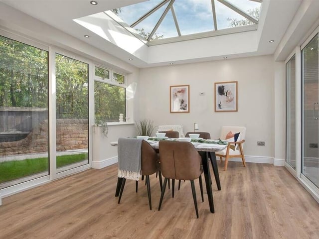 At one end of the kitchen is this dining area, which has a ceiling lantern, allowing in an abundance of natural light. It also includes a wood-effect vinyl floor, three double-glazed windows to the side of the house and two sets of double-glazed sliding doors leading out go the back garden.