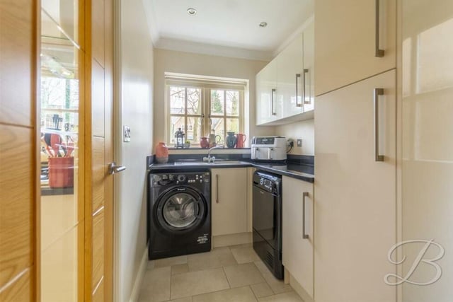 Next to the kitchen is this handy utility room, which has space and plumbing for a washing machine. The room is fitted with cabinets providing additional storage, a work surface and an inset sink with mixer tap. The floor is tiled.